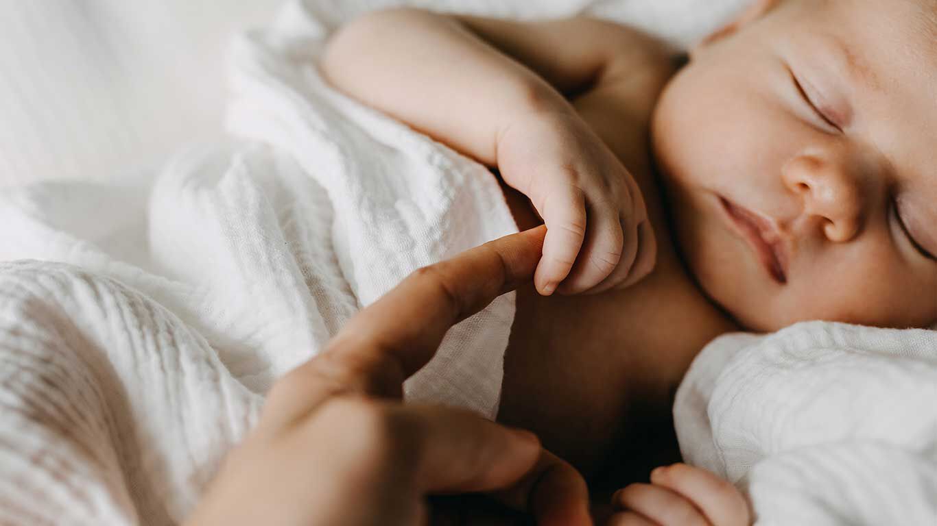 Slapende baby, gewikkeld in een witte mousseline doek.